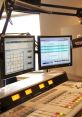 Professional radio broadcast studio setup featuring control panels and dual monitors for seamless programming.