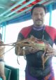 Diver holding a large lobster on a boat, showcasing the vibrant flavors of Cesarene seafood fishing.