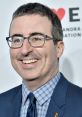 John Oliver smiles at an event, showcasing his signature style and representing modern satire and commentary in media.
