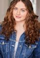 Portrait of a woman with curly hair wearing a denim jacket, showcasing a natural and approachable expression.