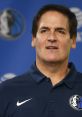 Mark Cuban speaking at a Dallas Mavericks press conference, wearing a team polo and showcasing team spirit.
