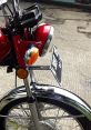 Close-up of a red motorcycle's front, showcasing the headlight, turn signal, and chrome details. Perfect for L2 enthusiasts.