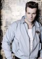 Stylish man in a light blue jacket poses confidently against a vintage rock and roll backdrop, embodying retro fashion.