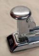 Close-up of a chrome stapler, showcasing its sleek design and sturdy construction, ideal for office use and organization.
