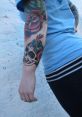 Colorful tattoo of a skull and roses on a person's arm, showcasing vibrant ink artistry and style.
