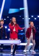 Three young singers perform on stage, showcasing their talent and passion for music during a kid voice competition.