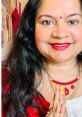 Woman in a red outfit with jewelry, smiling with hands in a prayer position, showcasing positivity and cultural expression.