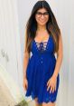 Mia Khalifa smiles, wearing a stylish blue dress with a lace design, showcasing her fashion sense and confident personality.