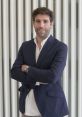 André Sidnei Rodrigues stands confidently in a blazer, showcasing a professional demeanor against a modern background.