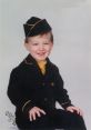 Smiling young boy in a vintage black and yellow outfit, exuding charm and innocence with a playful pose.