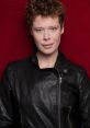 Marlene R in a stylish black leather jacket against a vibrant red background, showcasing a confident expression.