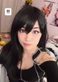 Emiru Bustos posing with a playful expression, showcasing long dark hair and vibrant blue eyes in a stylish outfit.