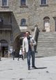 Dariusz Pruss strolling confidently in a historic Italian plaza, showcasing trendy fashion and vibrant surroundings.