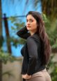 Confident Desi woman with long hair poses outdoors, showcasing modern fashion and natural beauty against a vibrant backdrop.