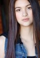Clara (Emily Sun) with long straight hair, wearing a denim vest, showcasing a natural and confident expression.