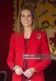 Elena in a vibrant red blazer, smiling confidently in an elegant setting, showcasing her poised presence.