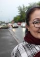 Smiling woman in a checkered shirt and scarf, standing on a busy street in Kazakhstan, capturing everyday urban life.