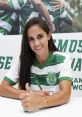 Brenda smiles and signs autographs wearing a green and white Sporting Portugal jersey, showcasing her enthusiasm.