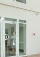 Svetlana standing by a glass door, wearing a mask in a modern, bright indoor space, showcasing a clean design.