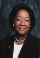 Professional portrait of a smiling woman in a black suit, representing themes of empowerment and leadership.