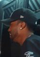Man with a baseball cap and earrings, smiling, in a dimly lit setting, expressing excitement or joy. Shouting Tony.