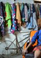Colorful fabrics hang on a wall behind a person seated in an orange chair, enhancing the vibrant South African atmosphere.